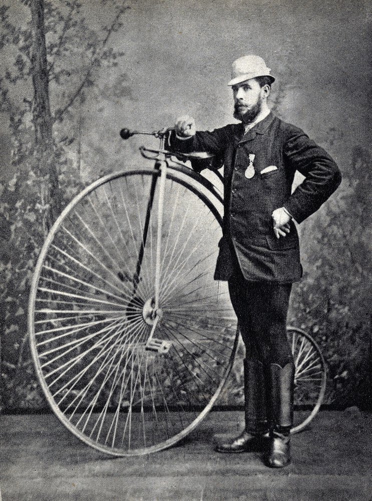 Homme posant avec le grand bi, l'ancêtre du vélocipède