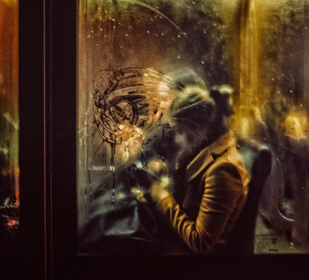 Une femme devant une fenêtre sous la pluie - Maciej Przeklasa