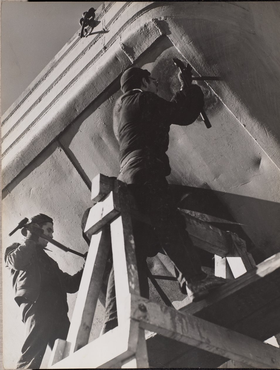 [Deux hommes travaillent sur le dessous d