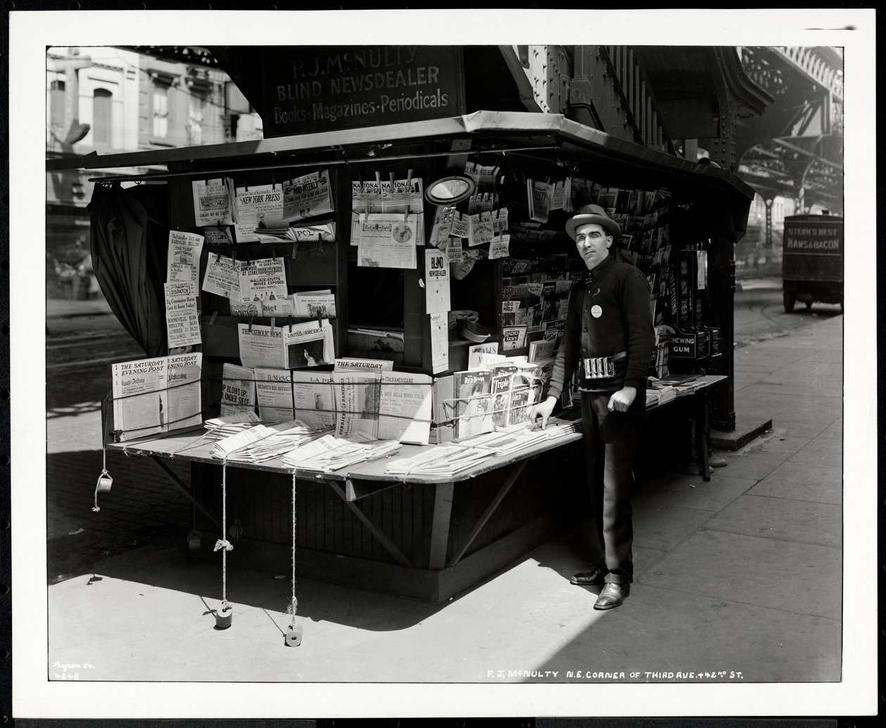 Marchand de journaux aveugle P.J. McNulty à son stand au coin nord-est de 3rd Avenue et 42nd Street, New York, 1926 - Byron Company