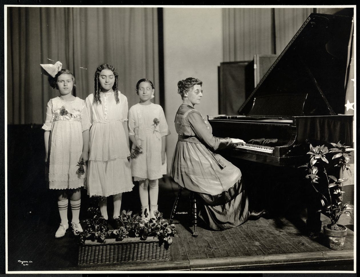 Femme jouant du piano tandis que trois filles chantent à l