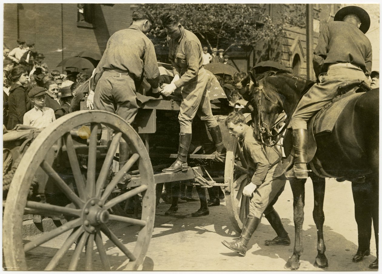 Photographie horizontale sépia montrant des hommes en uniforme déchargeant un objet drapé dans le drapeau américain, probablement un cercueil, d