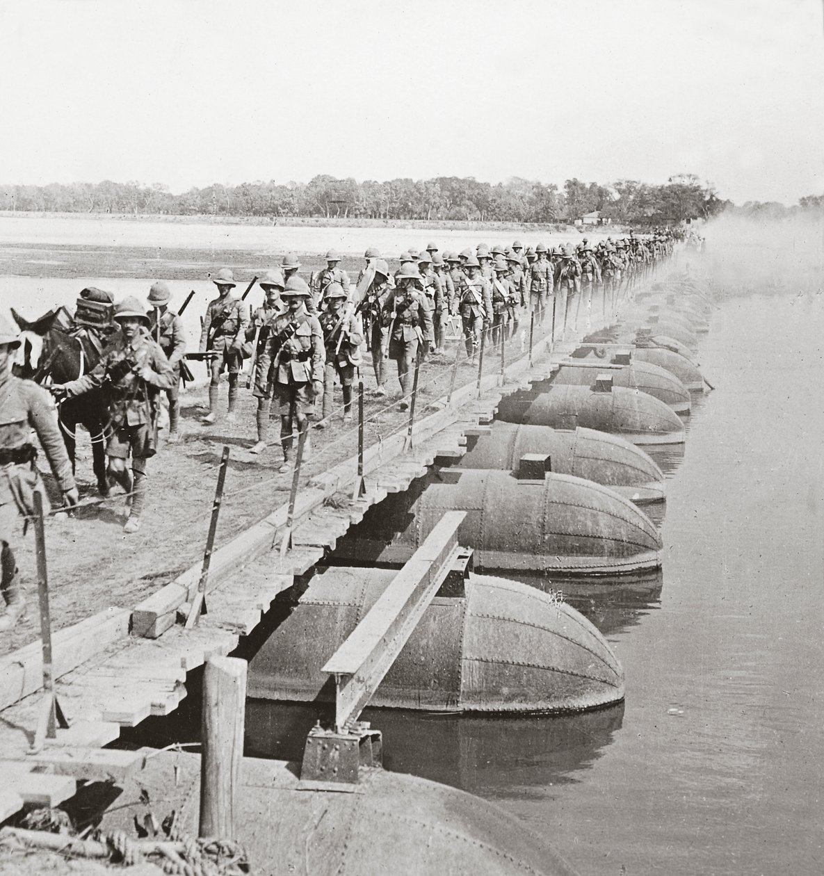 Section de mitrailleuses et infanterie traversant une rivière inondée par un pont de pontons - English Photographer
