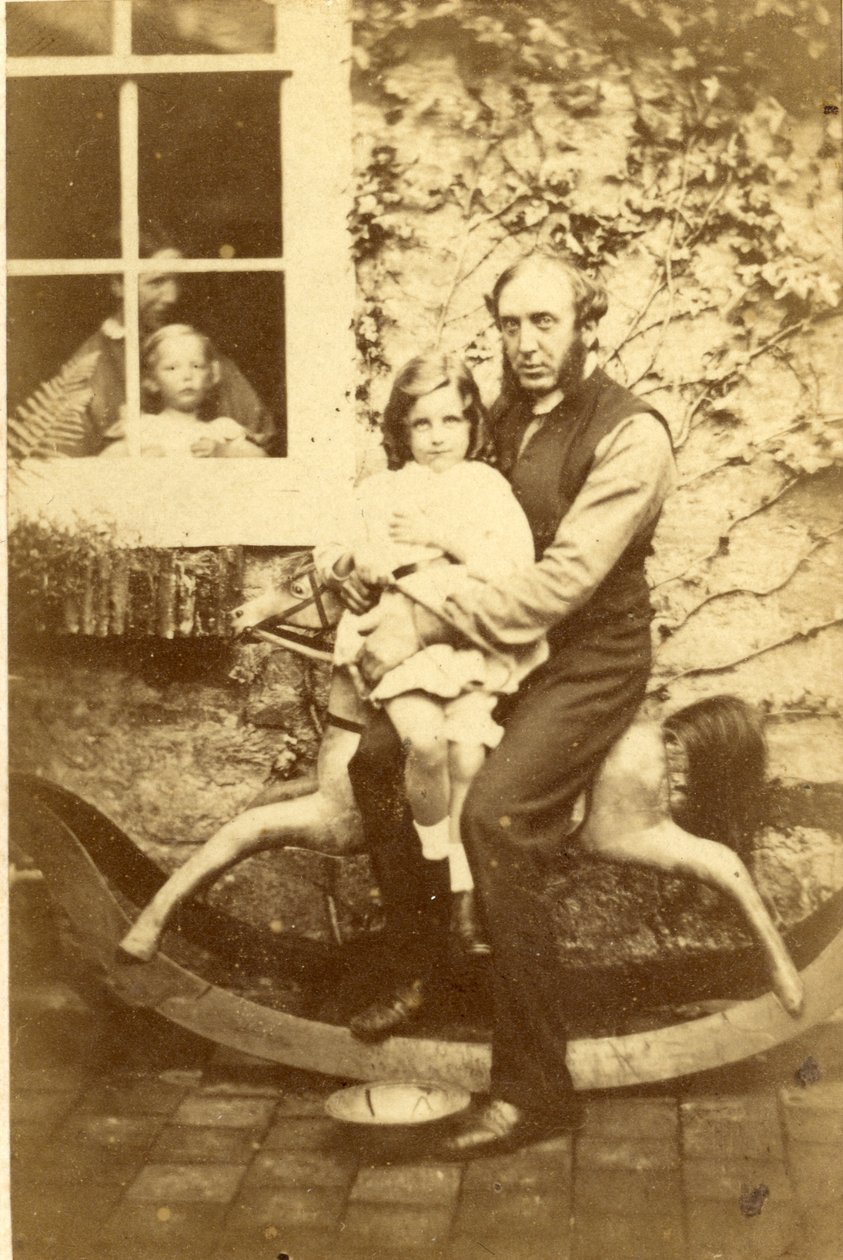 Père et fille assis sur un cheval à bascule avec frère et mère regardant par la fenêtre, années 1860 - English Photographer