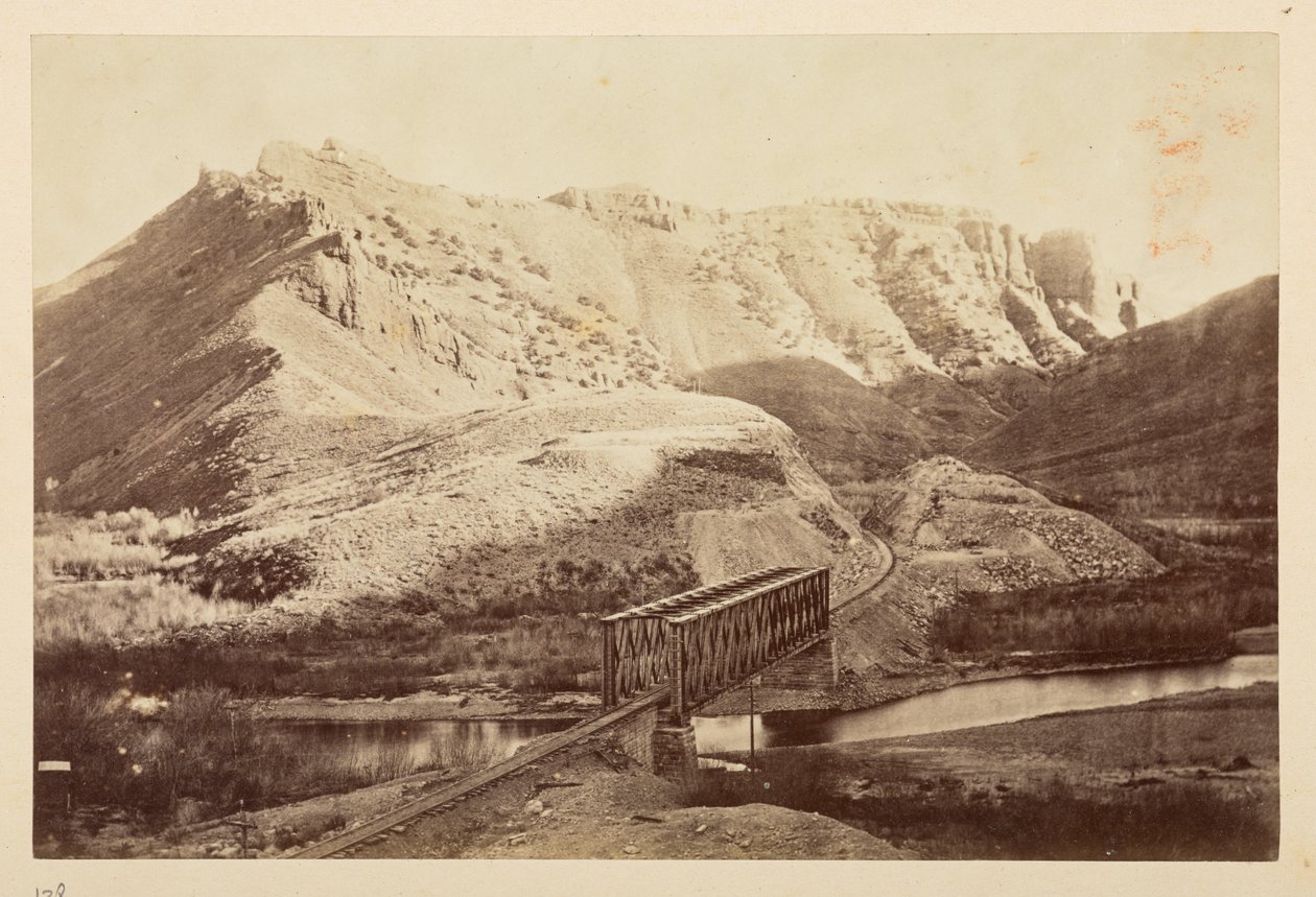 Vues sur le chemin de fer du Pacifique, de la voie ferrée traversant une rivière sur un pont en treillis, avec des montagnes au-delà - English Photographer