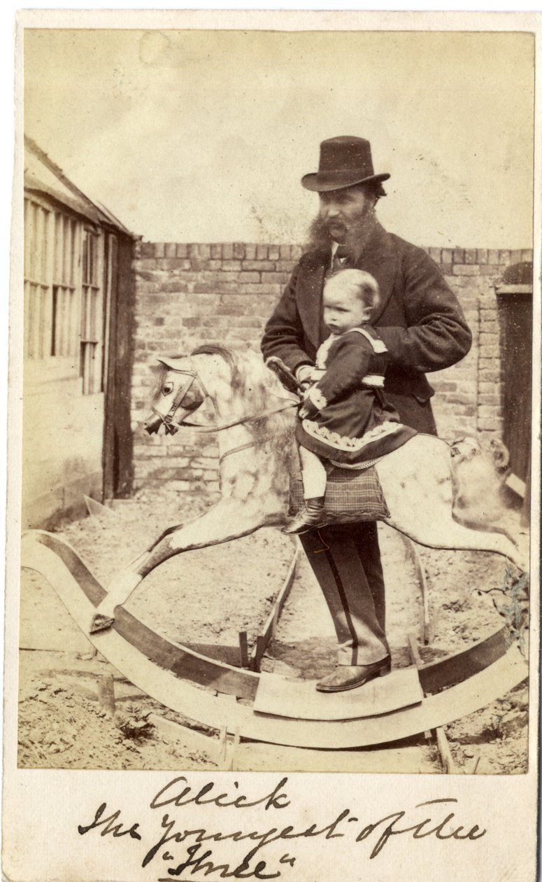 Jeune fille sur un cheval à bascule dans le jardin, son père à côté - English Photographer