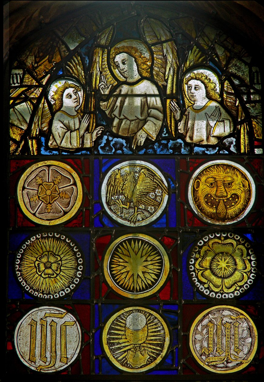 Un panneau dans la fenêtre est représentant des anges au-dessus de 9 médaillons avec des éclats de soleil, des roses, une tête de léopard, un calice et des monogrammes - English School
