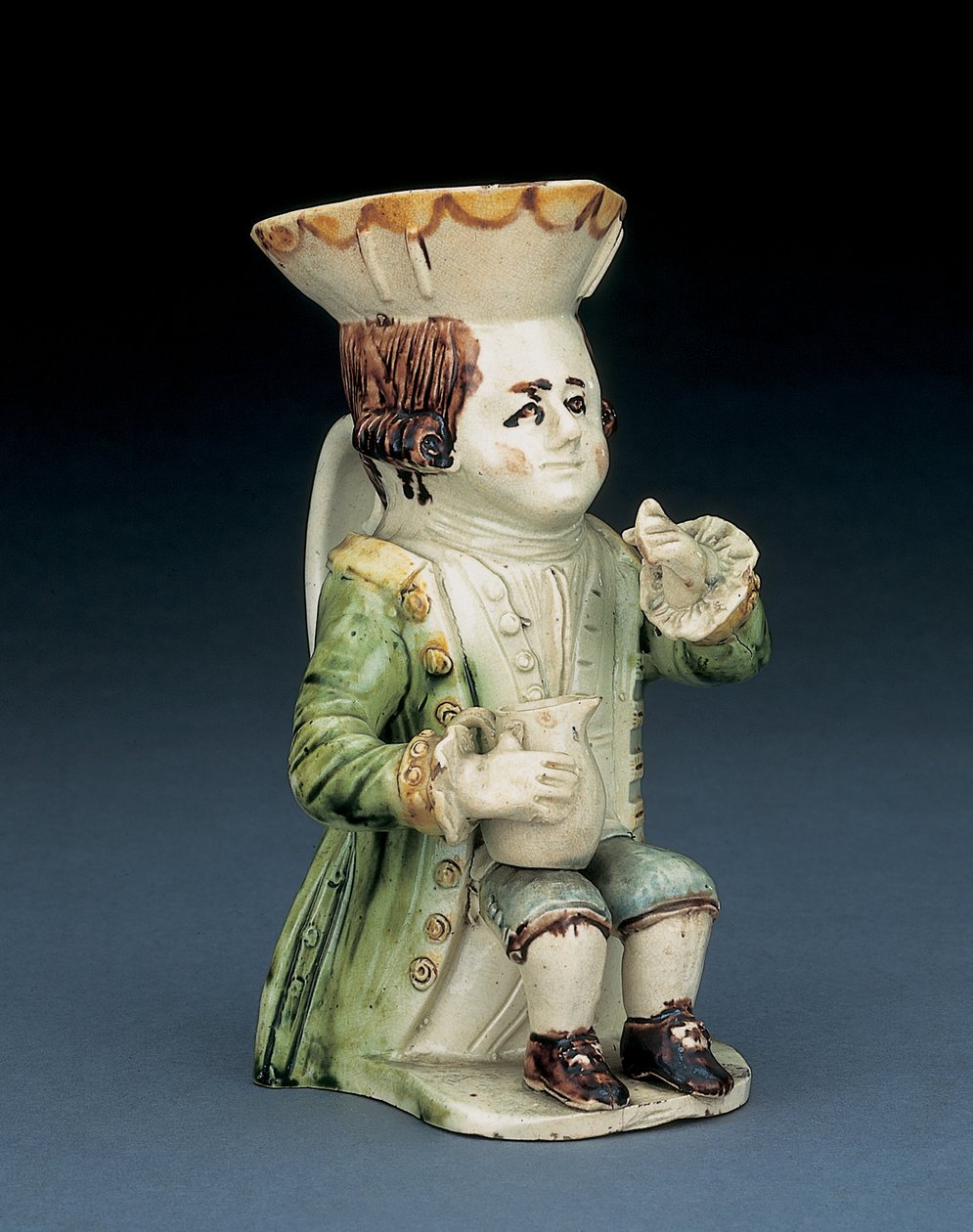 Cruche Toby buveur, son chapeau avec bord festonné brun et jaune, ses cheveux bruns incisés en queue et avec une rosette blanche assis avec une cruche balustre sur son genou, c.1770 - English School