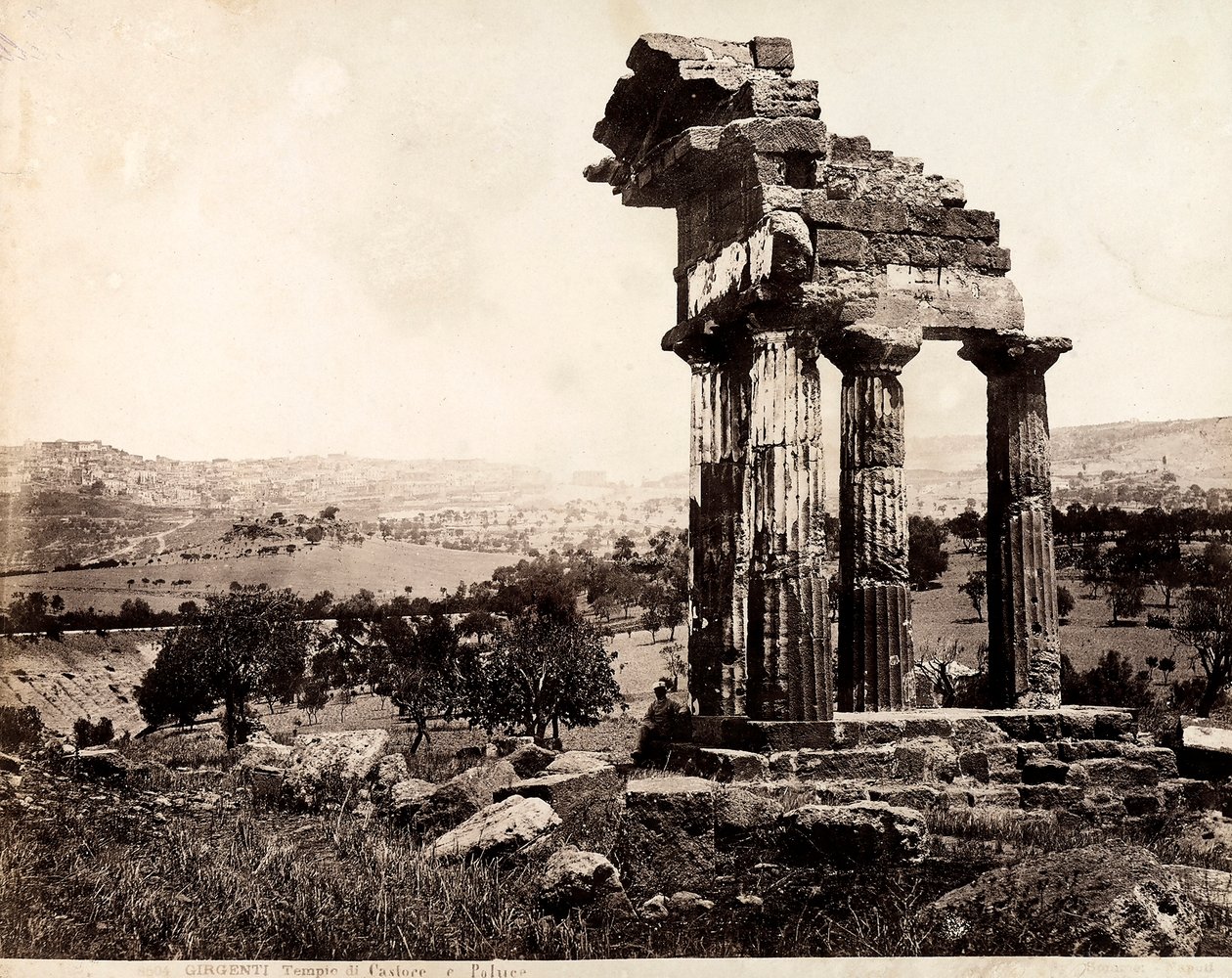 Vue des quatre colonnes restantes soutenant un entablement du Temple de Castor et Pollux dans la Valle dei Templi, Agrigente. Un panorama de la ville est visible à l