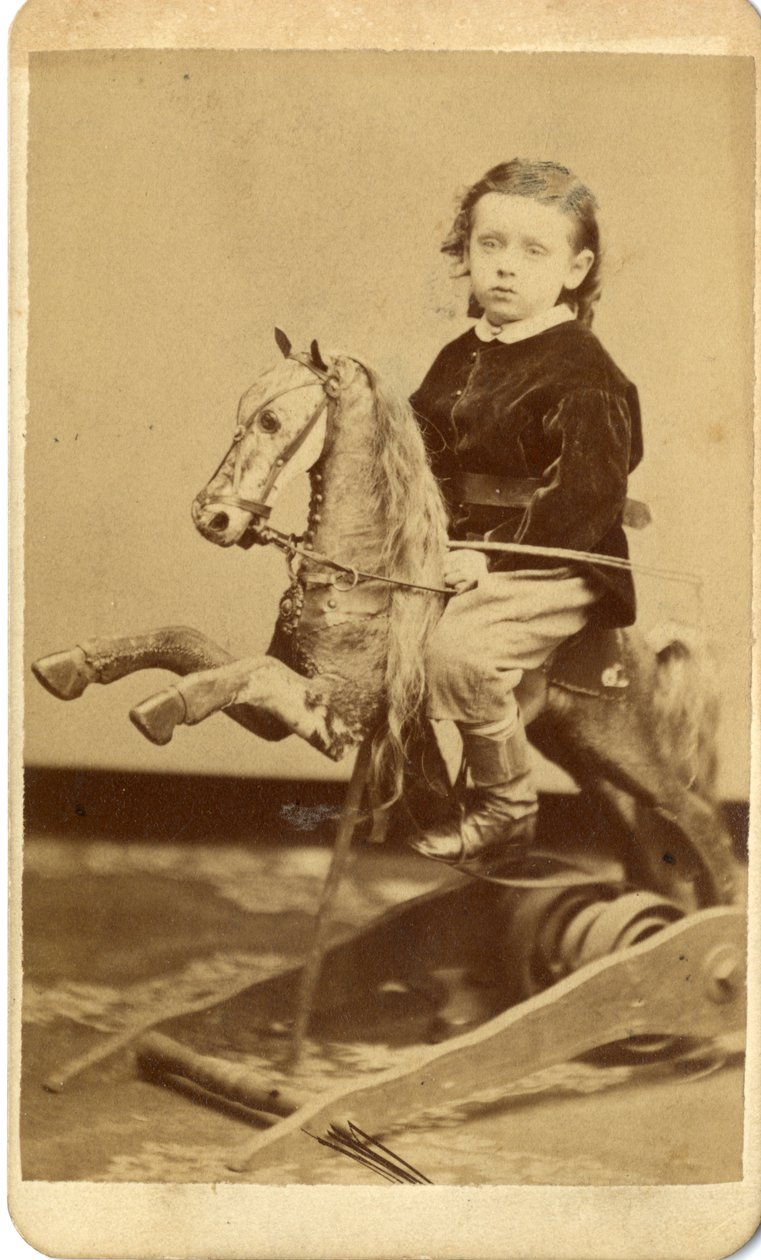 Jeune garçon avec fouet sur cheval à bascule - John McCaffrey