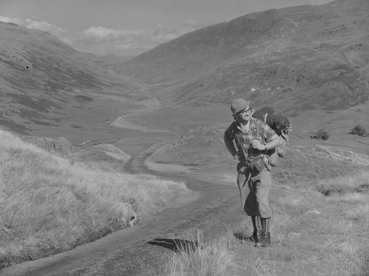 Un homme marchant avec un sac à dos sur le dos dans un paysage de vallée ouverte. - Joseph Hardman