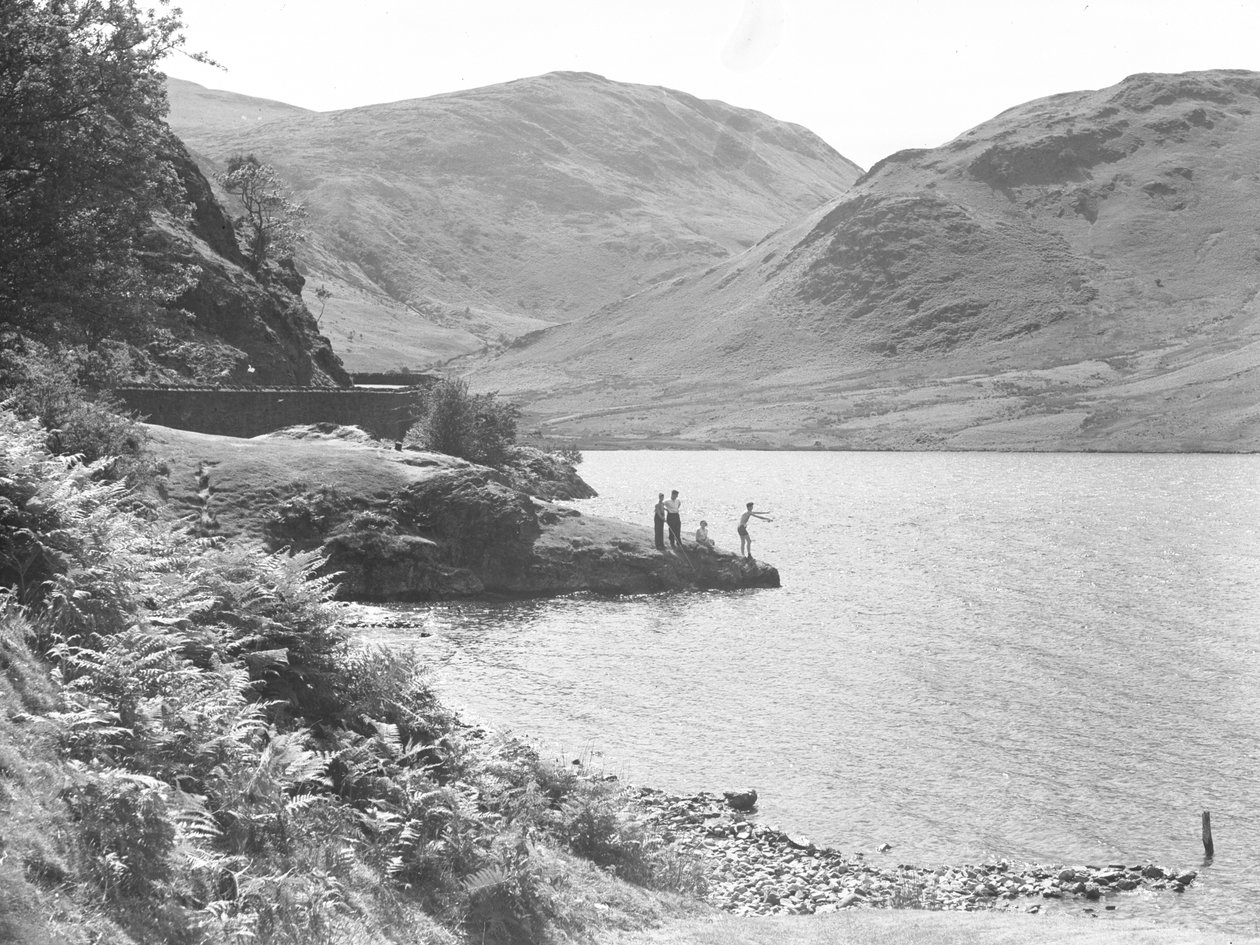 Trois hommes et une femme sur un affleurement rocheux dans le lac en train de pêcher, fells en arrière-plan - Joseph Hardman