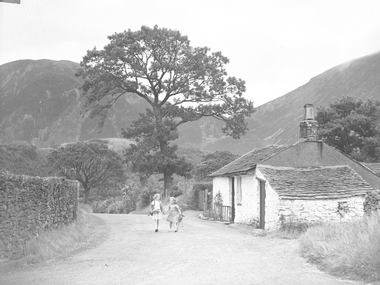 Deux jeunes filles se tenant par la main et tenant des brins de digitale, marchant sur la route, passant devant le cottage, en direction de l