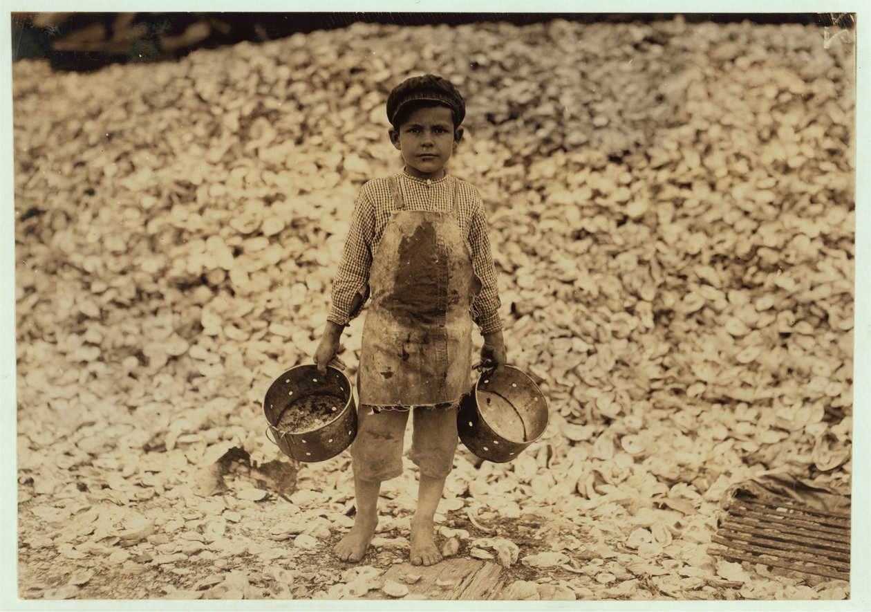 Manuel, 5 ans, migrant cueilleur de crevettes devant un tas de coquilles d