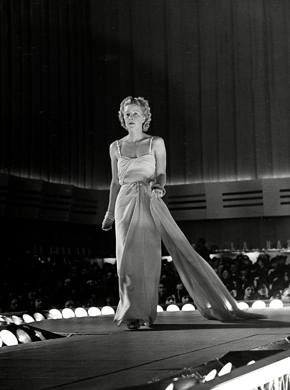 Mannequin photographié sur un podium en robe de soirée avec des bretelles en strass ; l