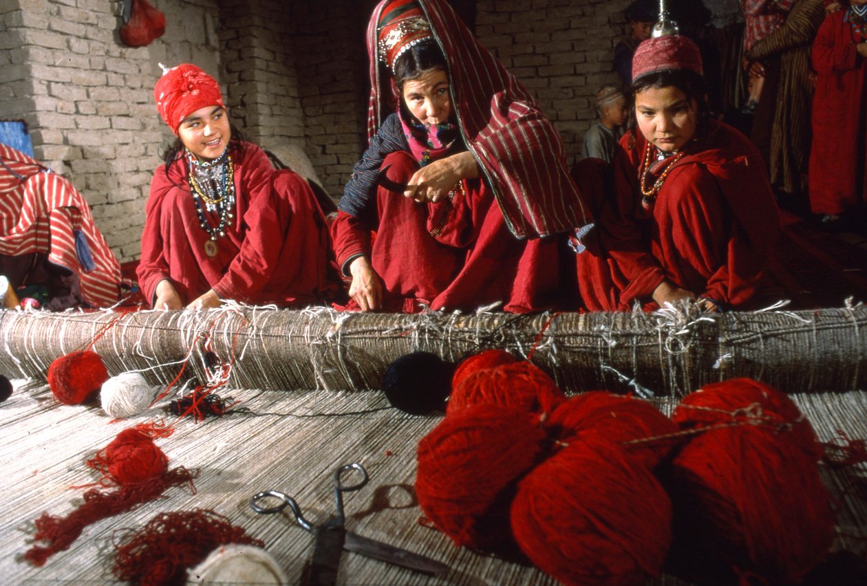 Femmes tisserandes turkmènes coupant les nœuds dans la chaîne d