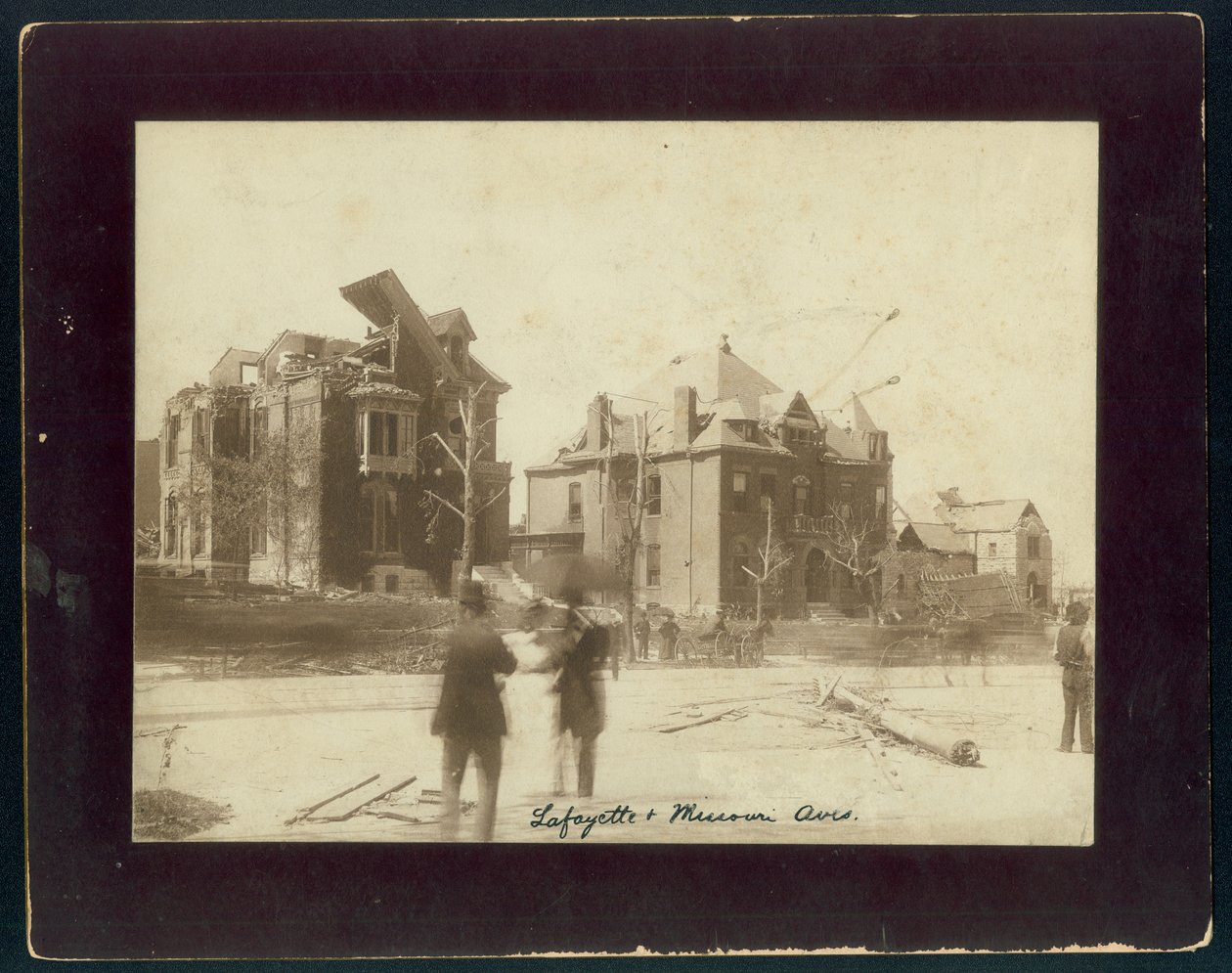 Photo horizontale sépia montrant trois maisons partiellement détruites, des arbres dépouillés et des spectateurs regardant les dégâts causés par une tornade - Unbekannt Unbekannt