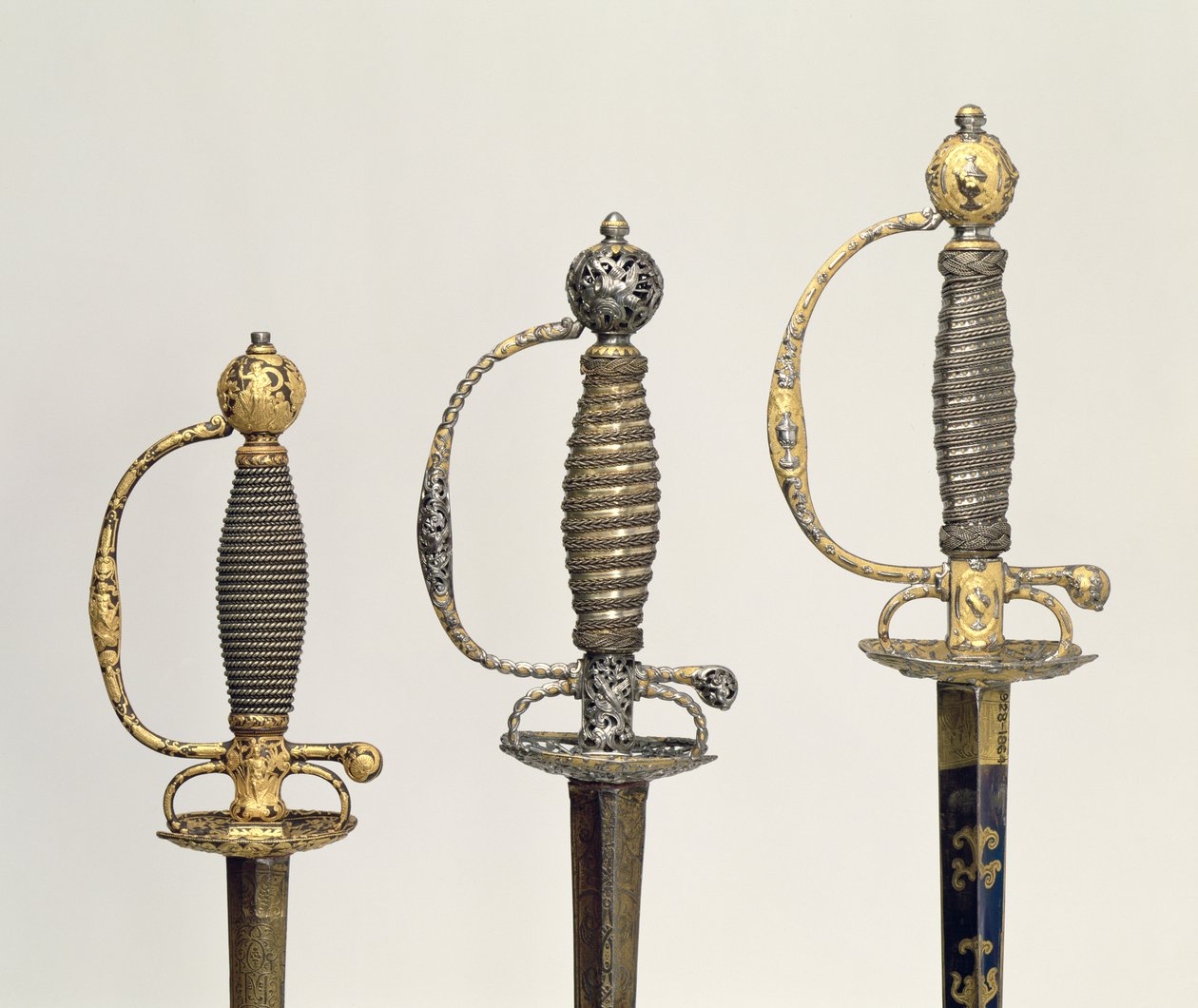 Poignées de trois épées françaises : une en acier, bleue et ornée de motifs en or ciselé, c.1730 ; une en acier percé et ciselé et le fond en or mat, c.1760 ; une en acier ciselé, gr - Unbekannt Unbekannt
