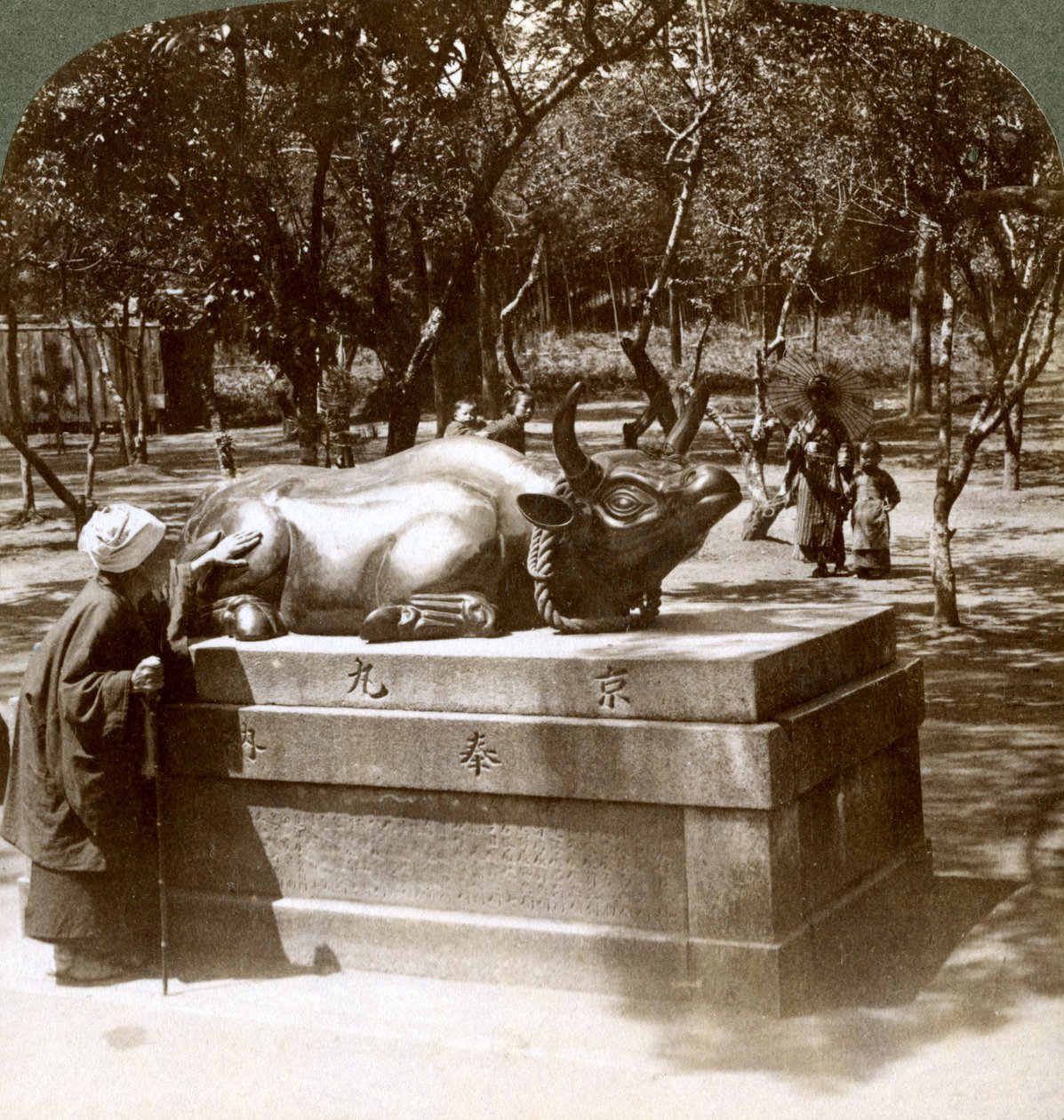 Femme dévote caressant un taureau en bronze pour guérir les rhumatismes, temple Kitano Tenjin, Kyoto, Japon, 1904 - Underwood and Underwood