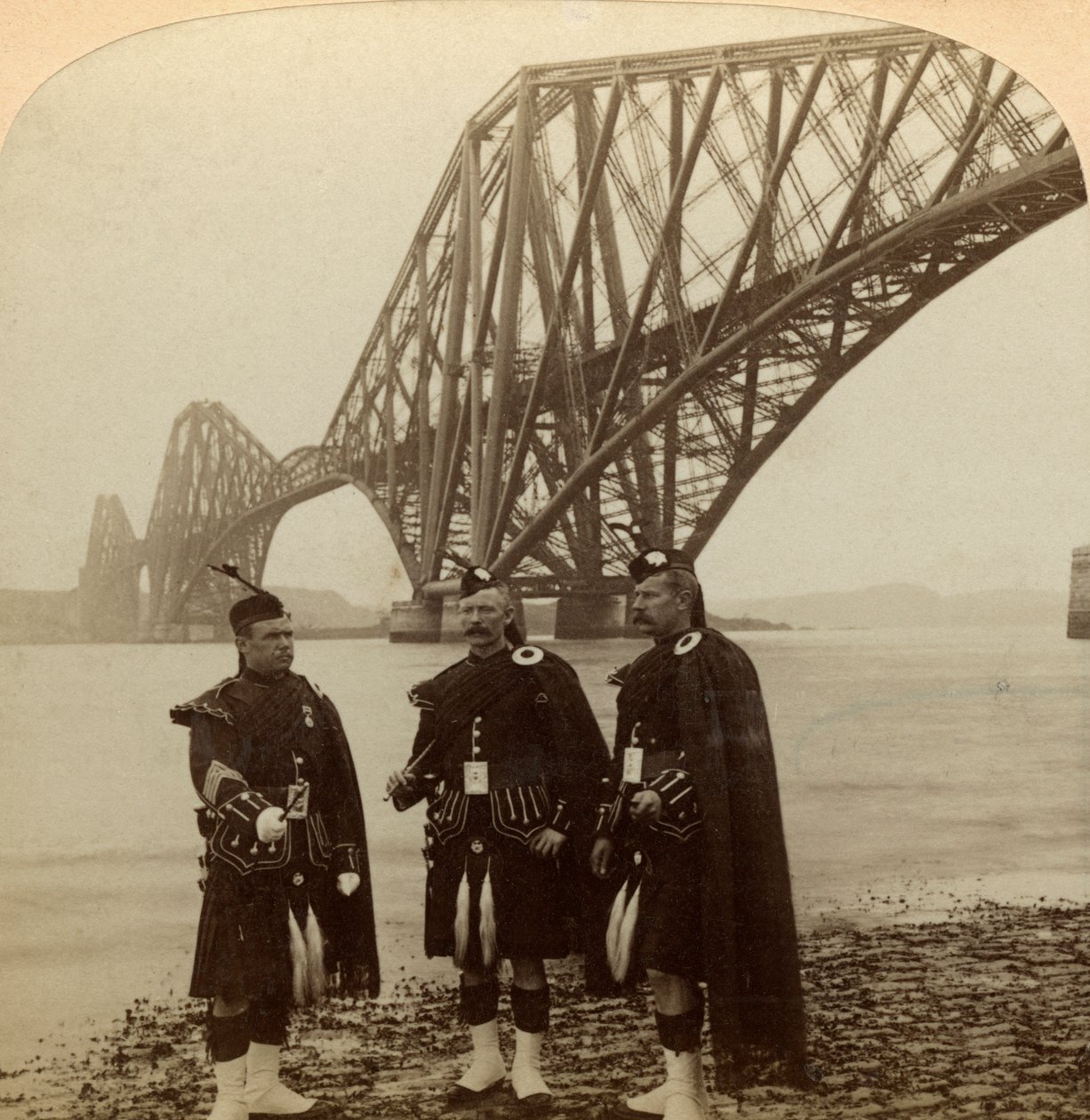 Hommes en costume écossais devant le pont du Forth, Écosse - Underwood and Underwood