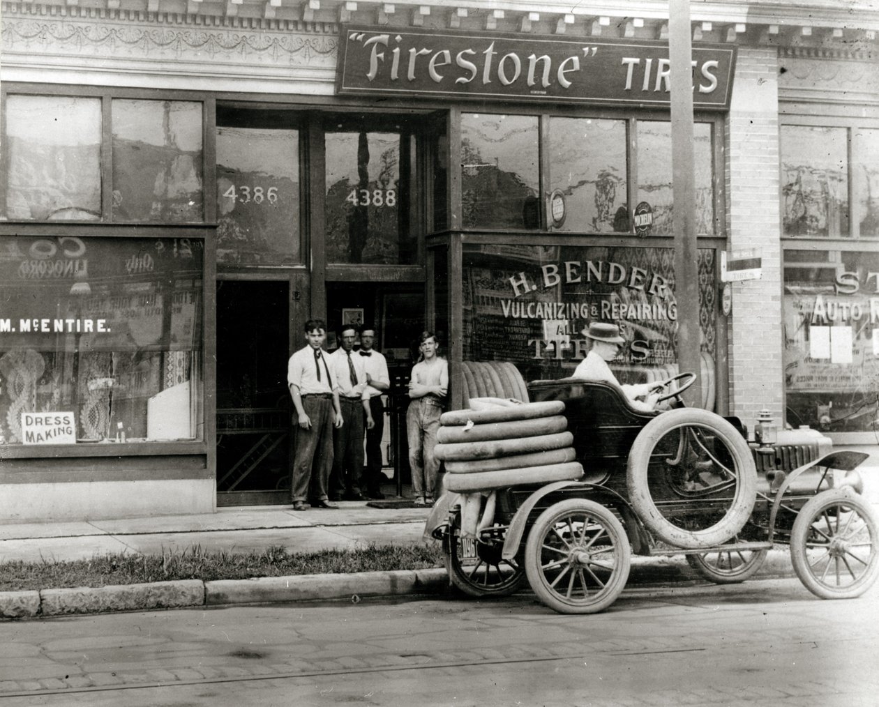Hommes et camion de réparation de pneus automobiles rassemblés devant la concession de pneus Firestone H. Bender au 4388 Olive Street - Unknown