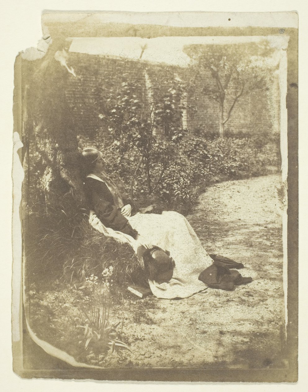 Mme Craik allongée dans le jardin avec un chapeau et un livre - Unknown