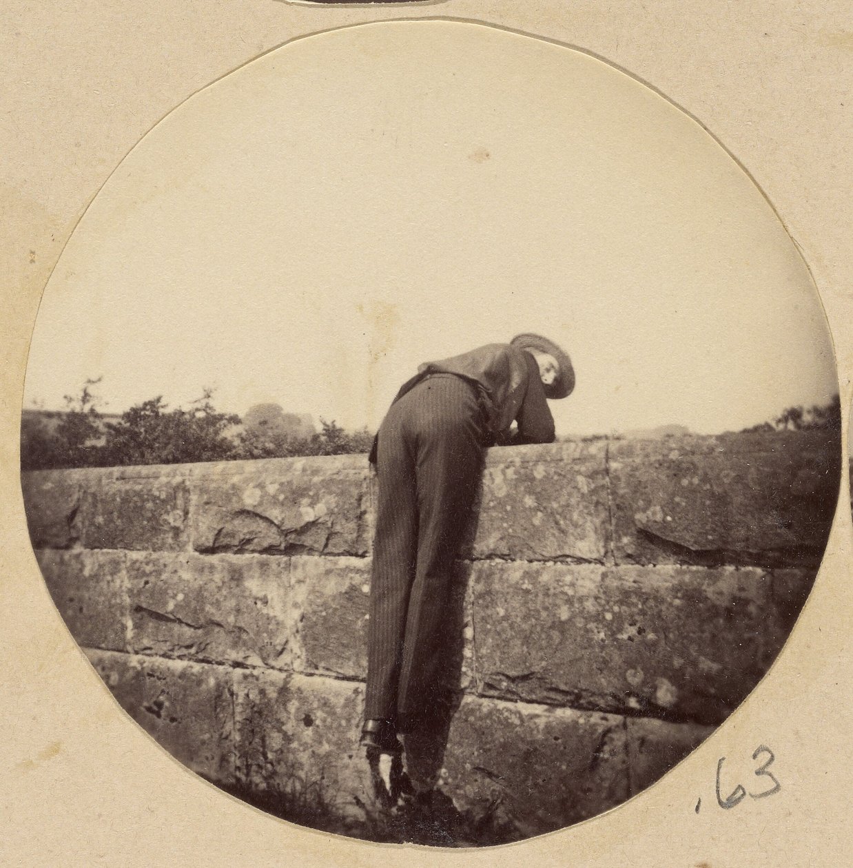 [Homme au chapeau penché sur un mur de pierre] - Unknown artist