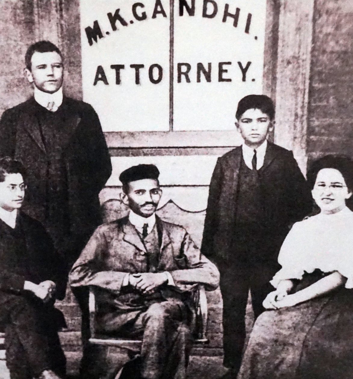 Mahatma Gandhi assis avec quatre associés devant son bureau d