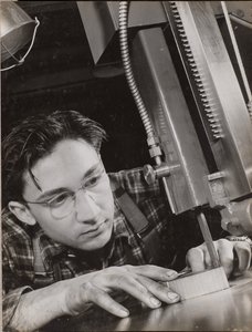 [Un homme portant des lunettes travaille intensément avec un dossier industriel]. - Arnold Eagle