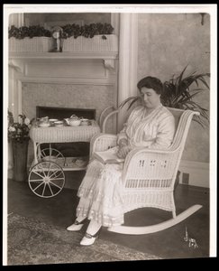 Mme Howard assise avec un livre dans un fauteuil à bascule chez elle au 200, 5e Avenue, New York, 1915-6