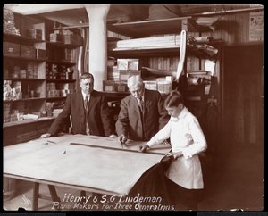 Portrait de Henry et S.G. Lindeman avec leur fils ou petit-fils debout sur des dessins de magasin pour un piano, 1910