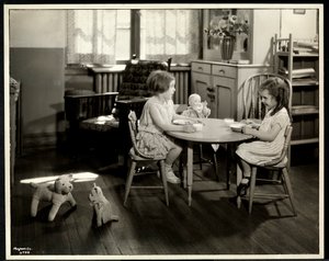 Deux filles aveugles ou malvoyantes mangeant à une petite table avec une poupée à l