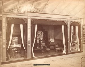 Exposition de James Shoolbred & Co. -- Bâtiment principal, Trois pièces avec meubles. La pièce de gauche contient trois armoires et une cuvette, un broc et un miroir ; la pièce centrale contient une table, des chaises, un canapé et un buffet avec un miroir - Centennial Photographic Co.