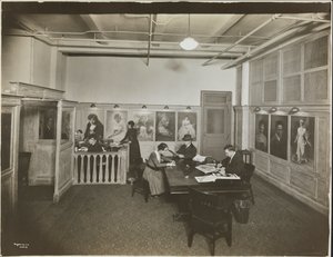Bureau principal/salle de réception à la Mutual Film Co. avec secrétaire au bureau, personnes à une table lisant, et portraits sur le mur, New York - Company Byron