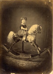 Jeune fille assise sur un cheval à bascule tacheté - English Photographer