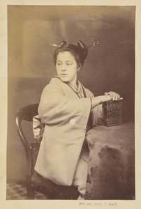 [Femme japonaise assise tenant un album de cartes-de-visite à une table]. - Felice Beato