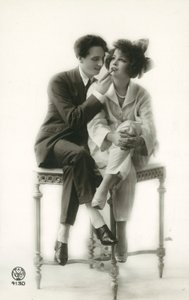 Homme androgyne en costume appliquant du rouge à lèvres à une fille en pyjama - French Photographer