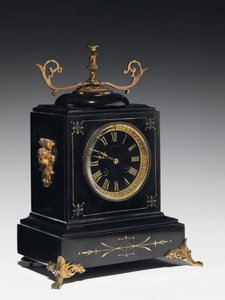 Une pendule de cheminée en pierre noire, avec décoration incisée, avec pieds, ornements et accessoires en laiton doré, par Jausions de Pau, France, vers 1876-78 - French School
