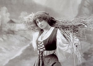 Jeune femme en tenue traditionnelle portant un fagot de paille