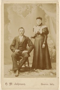 [Couple non identifié : homme moustachu assis, femme debout] - H. M. Johnson