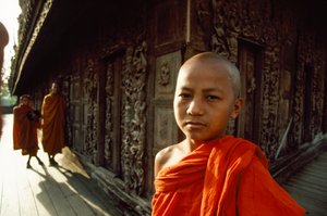 Un jeune novice moine devant des panneaux de teck sculptés. Monastère Shwenandaw, Mandalay, Birmanie