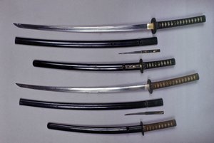 En haut : un katana, épée japonaise et son fourreau, wakizashi, épée courte japonaise dans son fourreau, petit poignard Kokatawa rangé dans le même fourreau. tous trois sont du 18e siècle. les inférieurs sont du 17e siècle