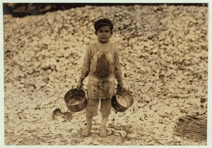 Manuel, 5 ans, migrant cueilleur de crevettes devant un tas de coquilles d