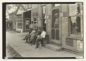 Hommes avec chien assis sur un banc devant un magasin général - Lewis Wickes Hine