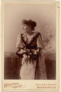 [Femme non identifiée de profil, appuyée sur une chaise, tenant un éventail de plumes].