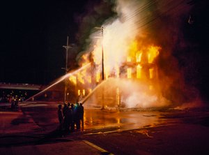 Un bâtiment urbain complètement englouti par le feu et les flammes la nuit à Kansas City avec des pompiers