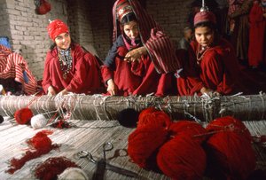 Femmes tisserandes turkmènes coupant les nœuds dans la chaîne d
