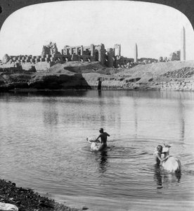 Vue sur le lac sacré vers le grand temple de Karnak, Thèbes, Égypte - Underwood and Underwood