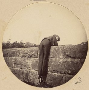 [Homme au chapeau penché sur un mur de pierre] - Unknown artist