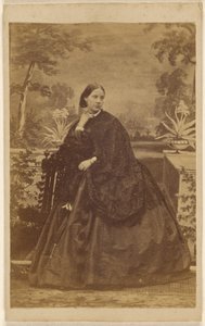 [Femme non identifiée assise, la main sur le col]